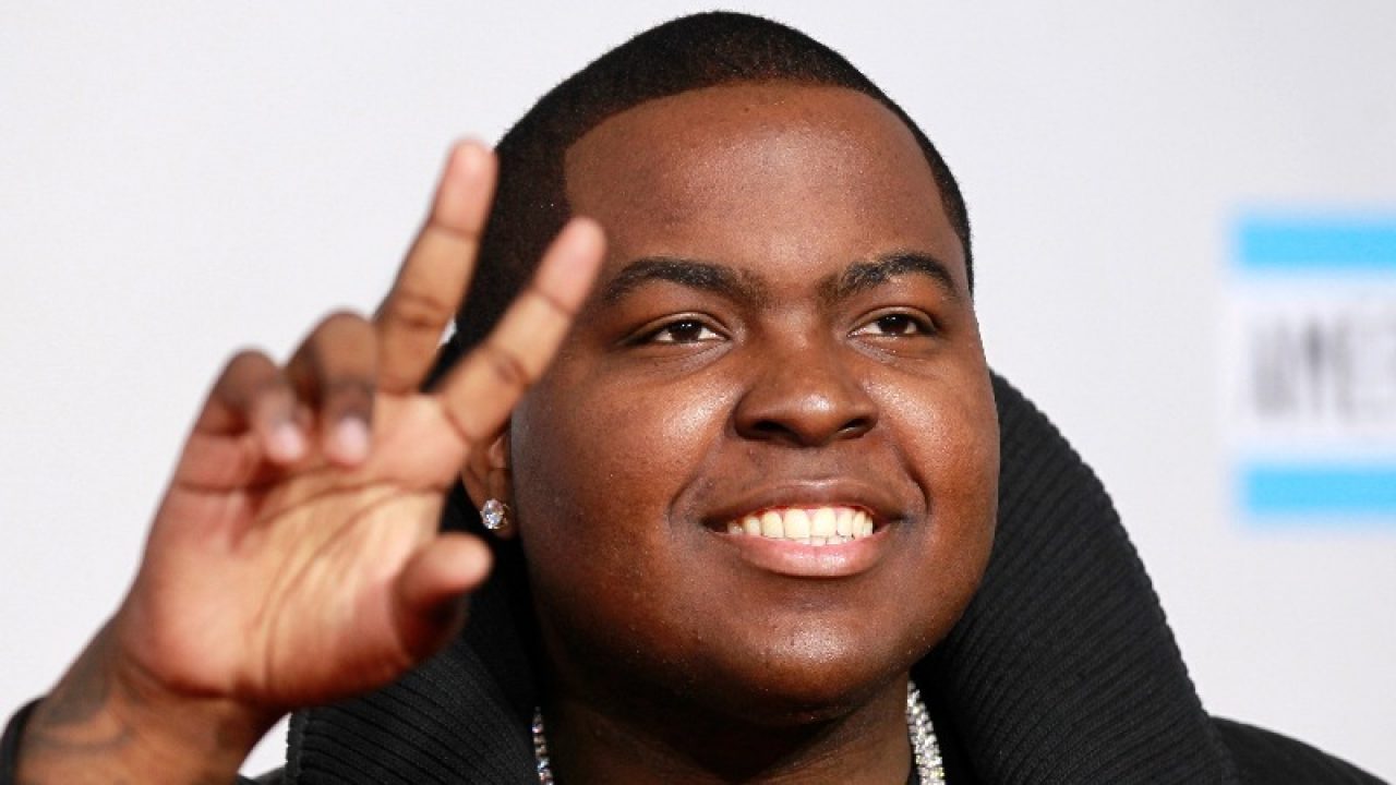 Sean Kingston is making a peace sign on the red carpet.