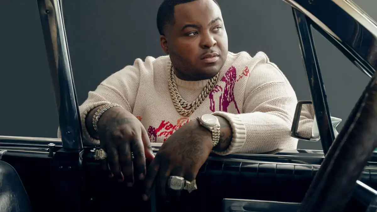 Sean Kingston is leaning into a car.