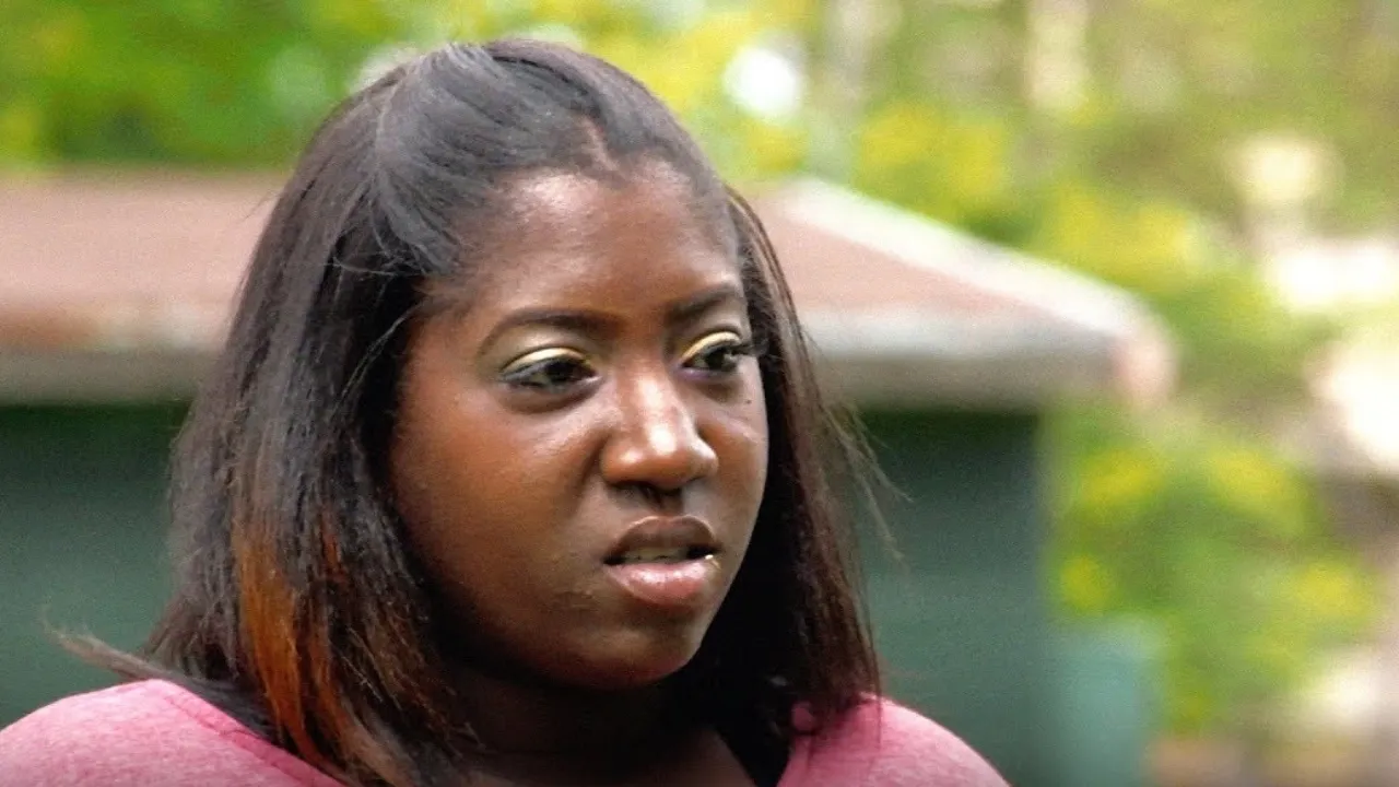 A woman is standing outside of a house on Catfish.
