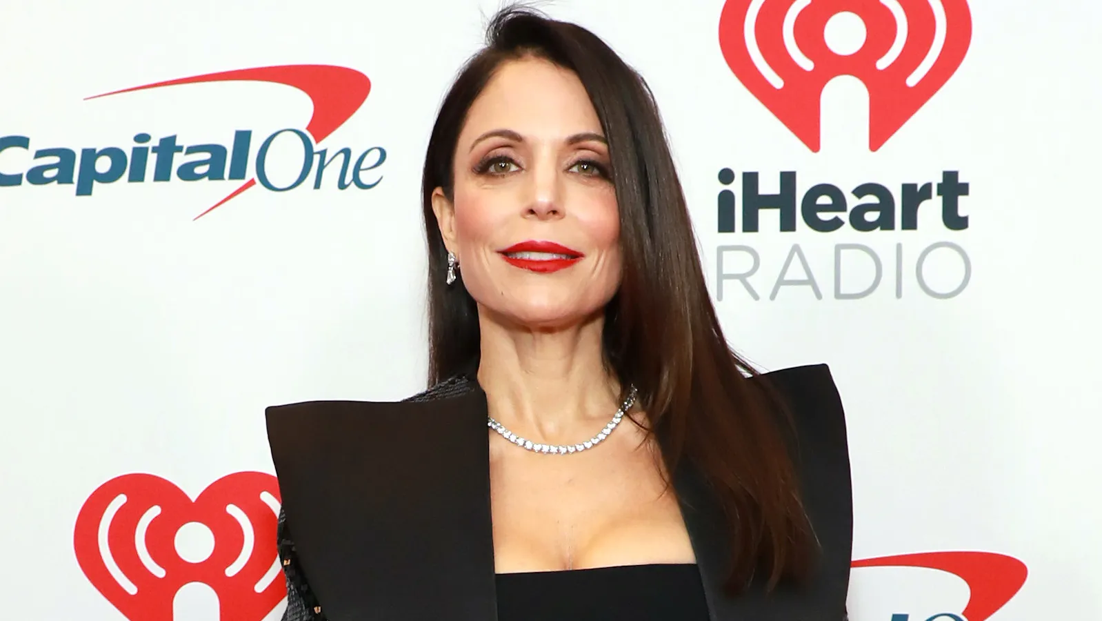 Bethenny Frankel from The Real Housewives of New York City is standing in front of an iHeart Radio sign.