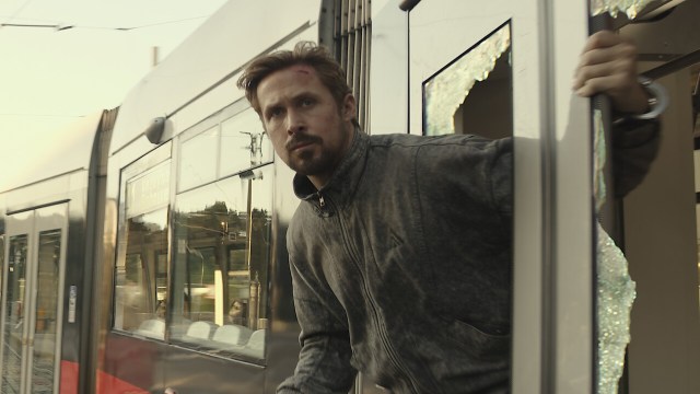 Ryan Gosling looks out of a broken window in The Gray Man