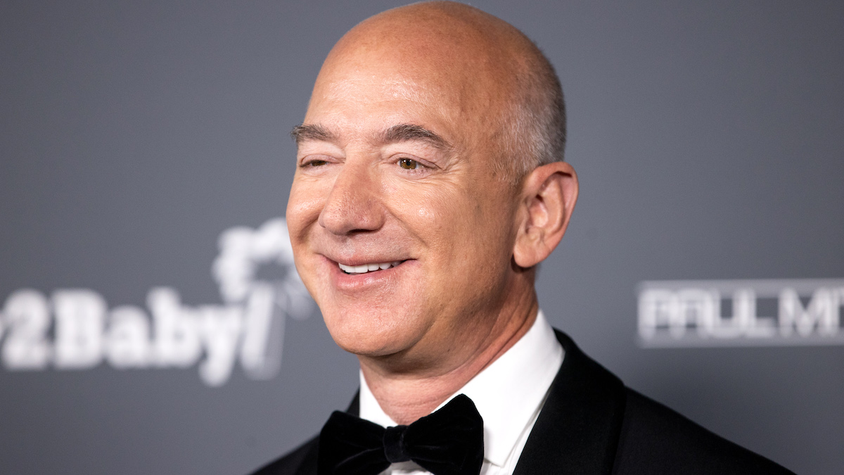 Jeff Bezos in a black and white suite, black bow tie, and standing in front of a blurred grey background