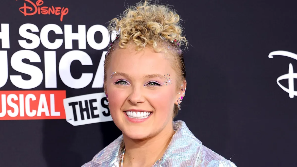 JoJo Siwa on the red carpet of 'HSMTMTS' smiling at the camera