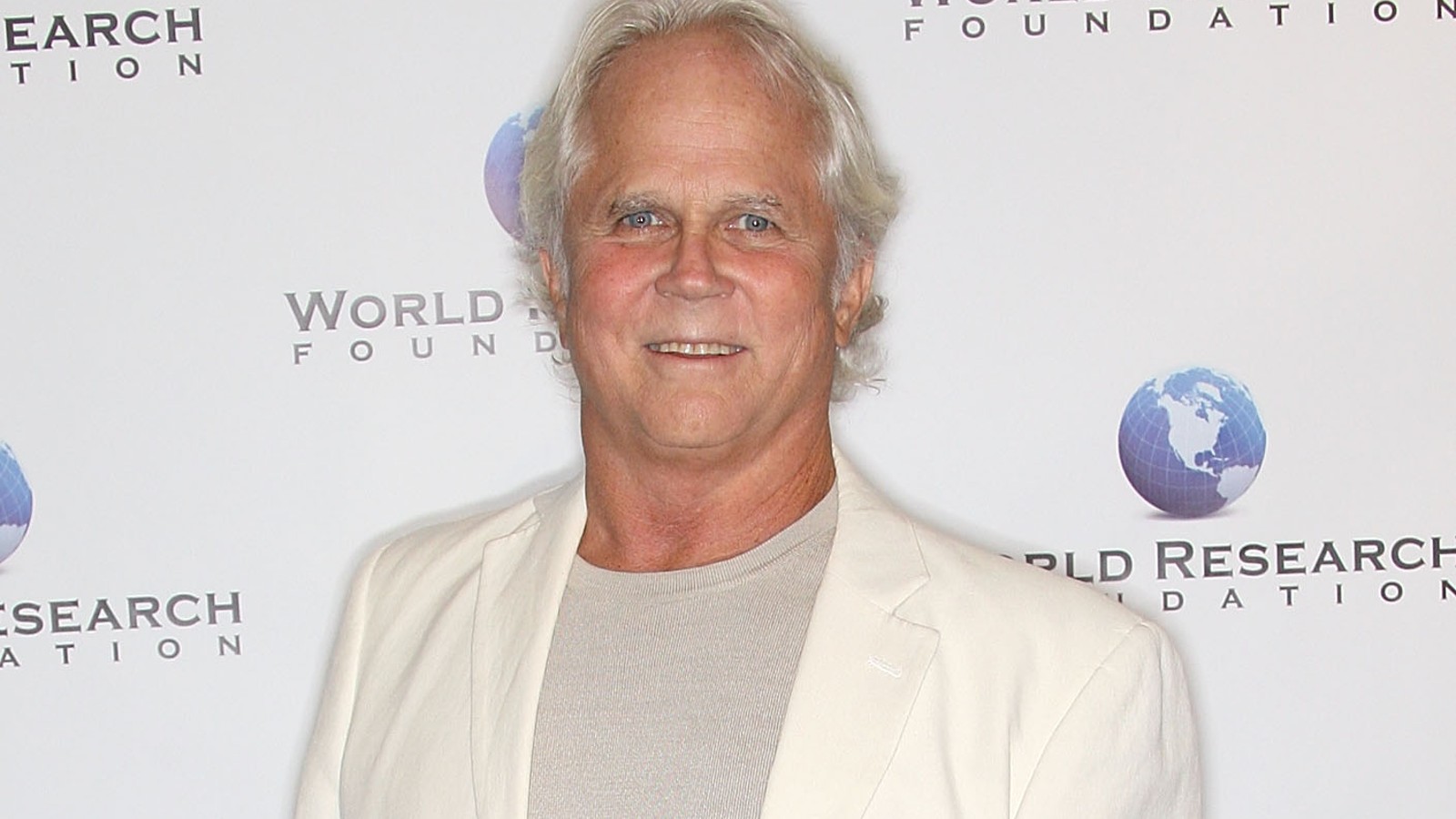 Tony Dow sports a white blazer and t-shirt at a red carpet event.