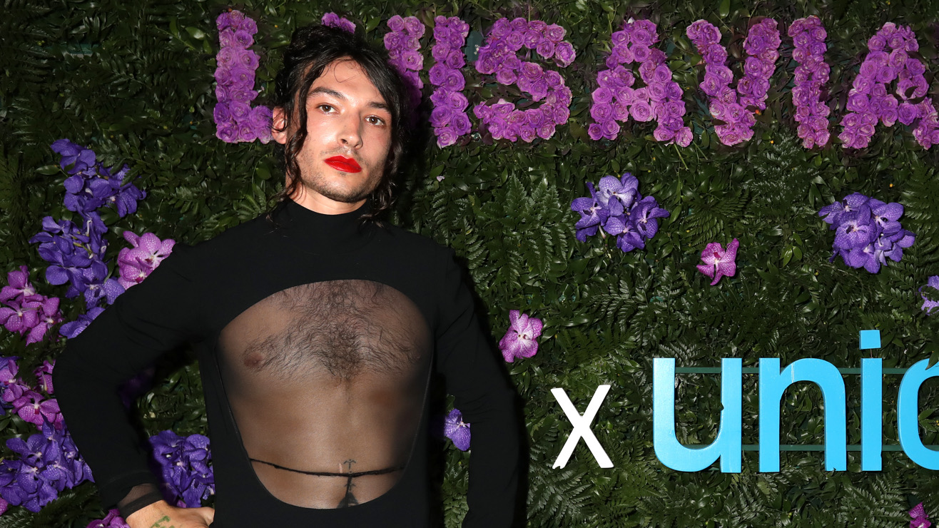 Ezra Miller attends the LuisaViaRoma for Unicef ​​photo shoot in a black dress with a sheer front panel.
