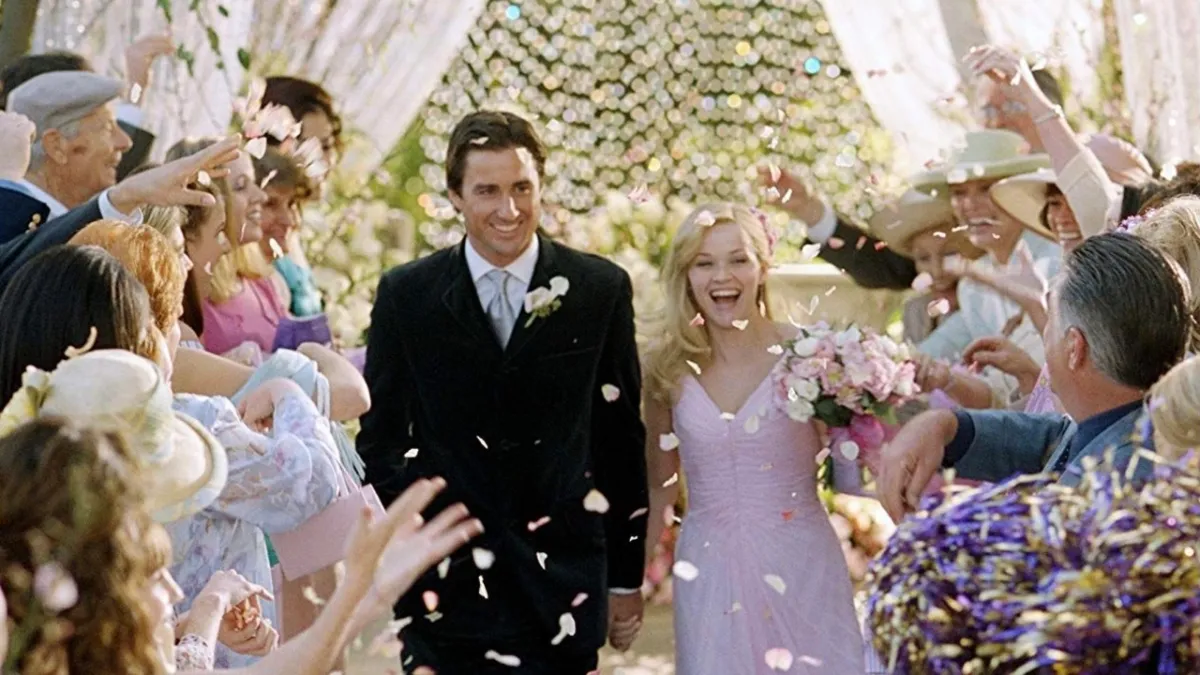 A still of Reese Witherspoon as Elle and Luke Wilson as Emmett at their wedding as flower petals rain down on them