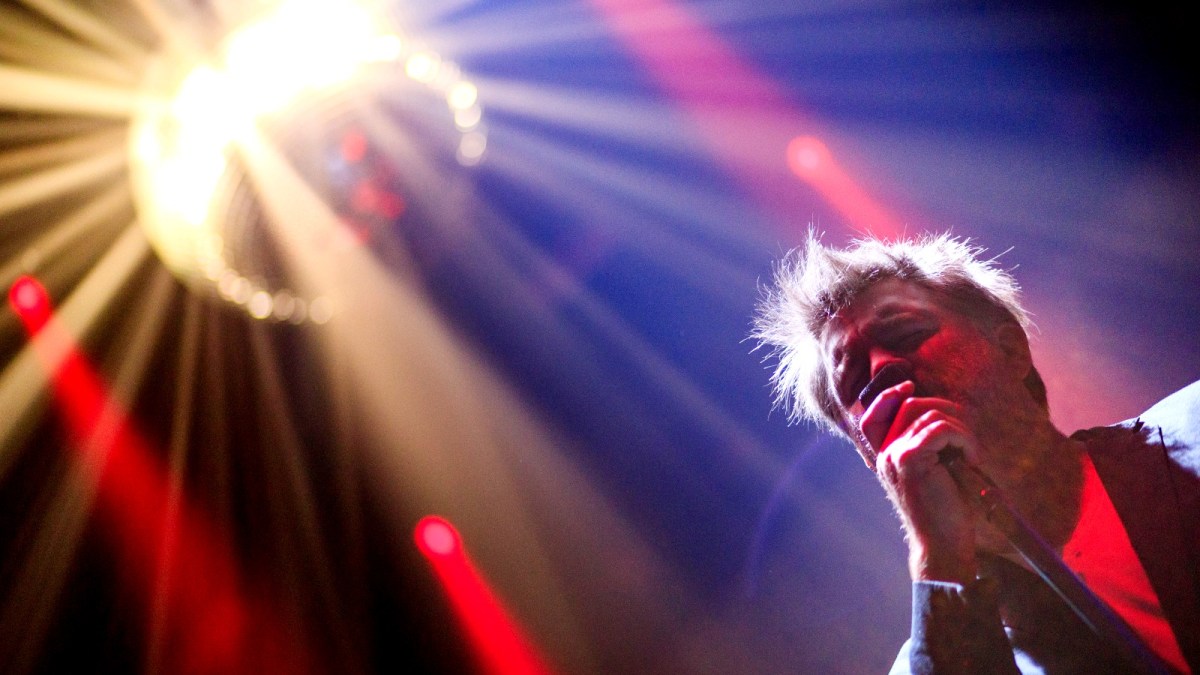 LCD Soundsystem front man James Murphy sings into a microphone during a concert.