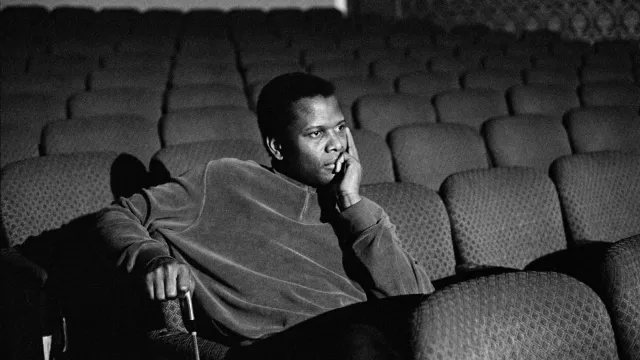 Sidney Poitier sits in a movie theater alone