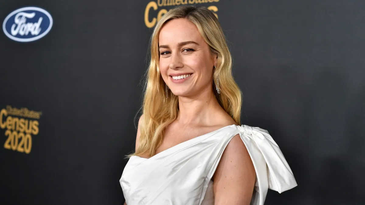 Brie Larson wears a white gown and shining smile at a red carpet event