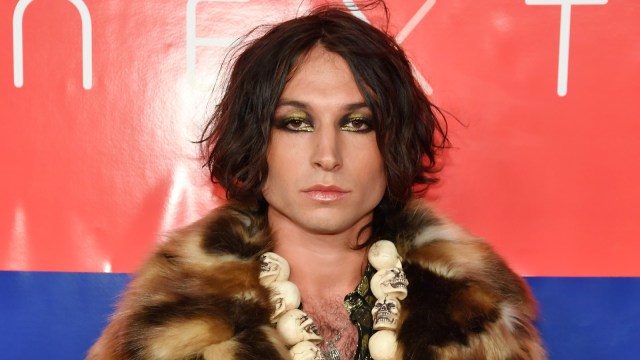 Ezra Miller sports a fur outfit on a red carpet.