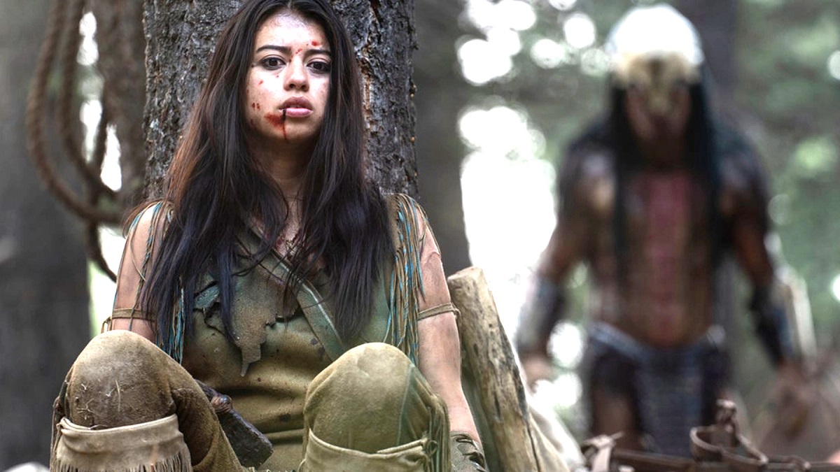 Amber Midthunder in character as Naru leans on a tree and gathers her wits as Predator hunts her in a still from “Prey”