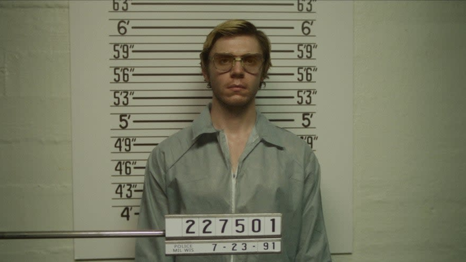 Evan Peters posing for a mugshot as Jeffrey Dahmer