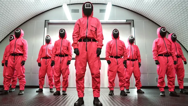 'Squid Game' soldiers wearing signature red track suit with black face covering lined up in a row