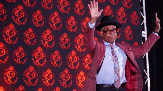 Giancarlo Esposito waves at a crowd of fans during a Q&A panel.