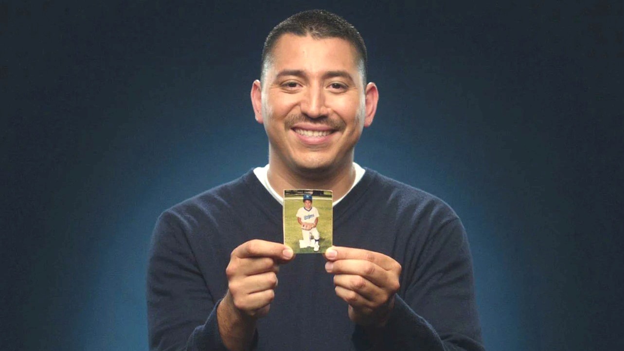 Juan Catalan holding a photo of his younger self in a Dodgers jersey