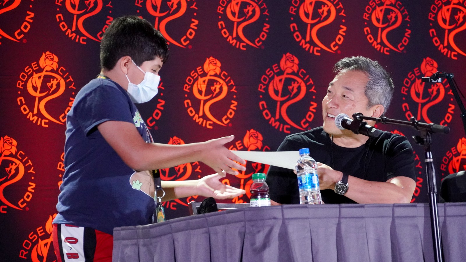 Jim Lee gives a fan a hand made original drawing at a comic con event.