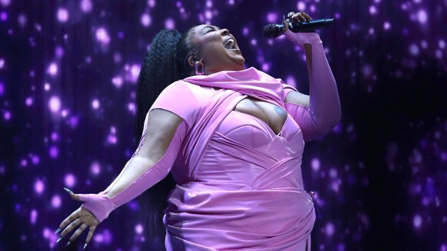 Lizzo sings into a microphone on a stage.