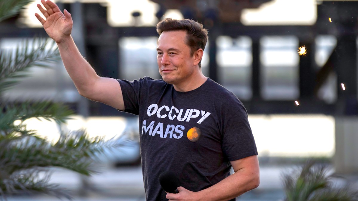 Elon Musk wearing an Occupy Mars shirt and raising his hand
