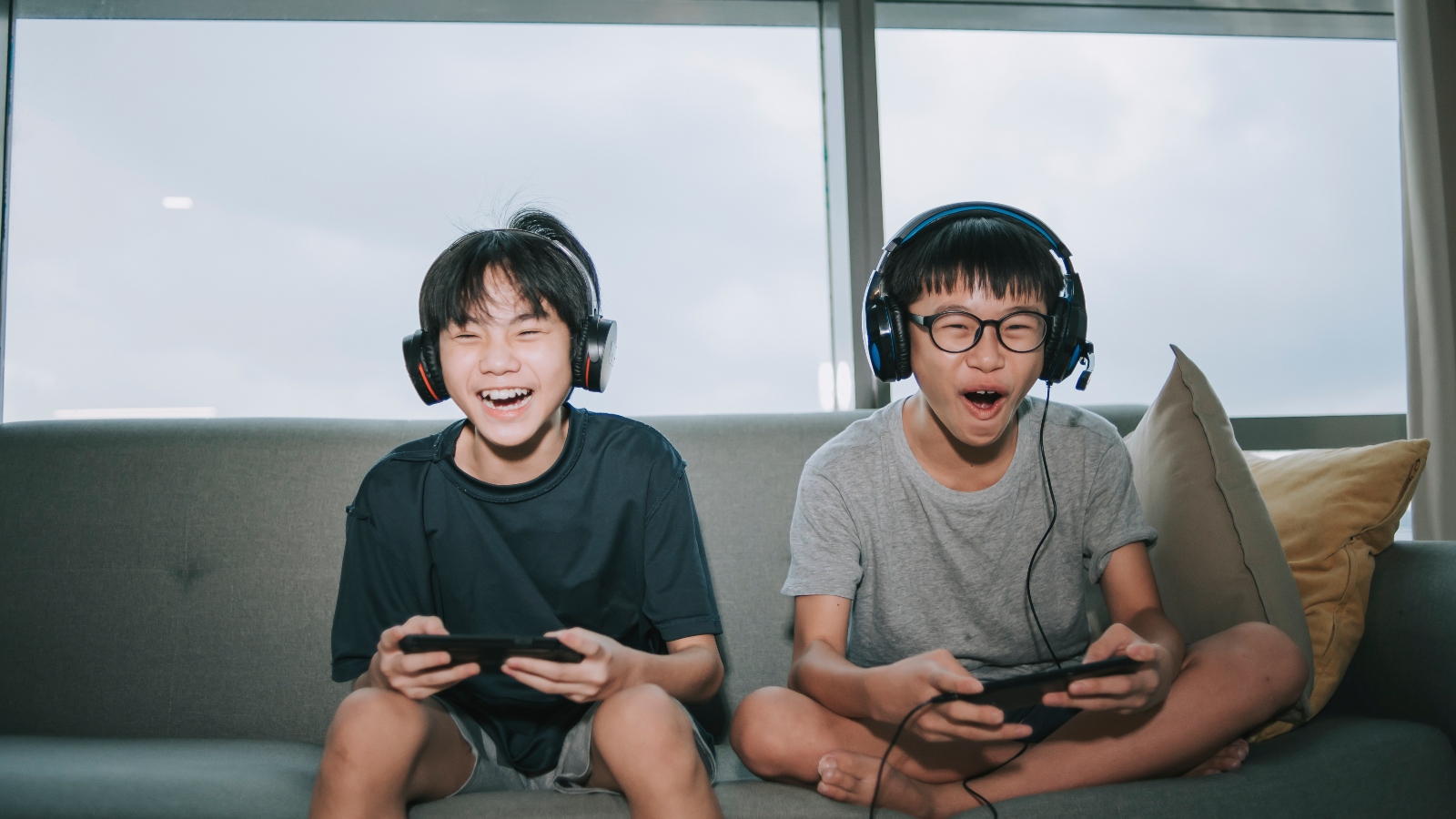 Two Asian brothers playing video games on a couch