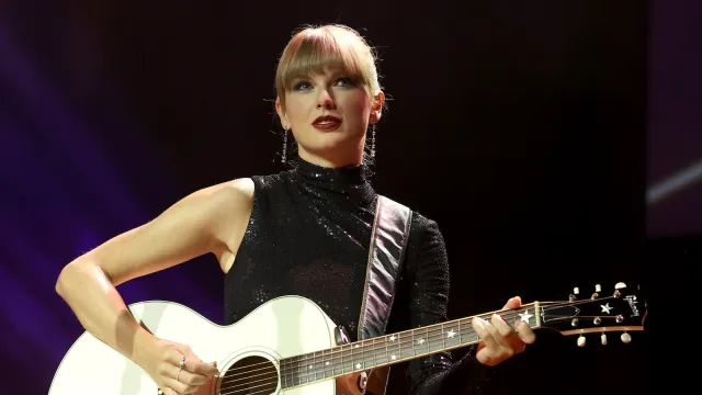 Taylor Swift plays guitar in black dress