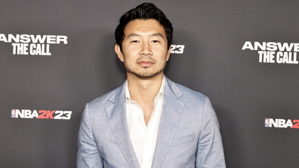 Simu Liu on the red carpet wearing a grey suit and white shirt