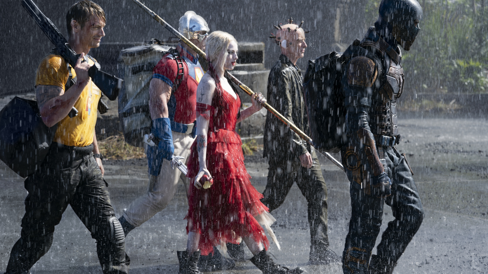 Harley Quinn (Margot Robbie), Bloodsport (Idris Elba), Colonel Rick Flag (Joel Kinnaman), and Peacemaker (John Cena) walk heroically during a downpour in 'The Suicide Squad' (2021).