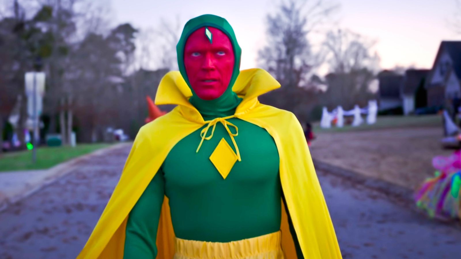 Vision in his Halloween costume walks through a deserted street in Westview in WandaVision. 