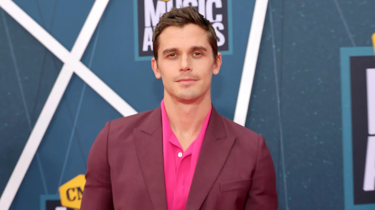 Antoni Porowski of Netflix's Queer Eye wearing a pink shirt and plum colored blazer on the red carpet