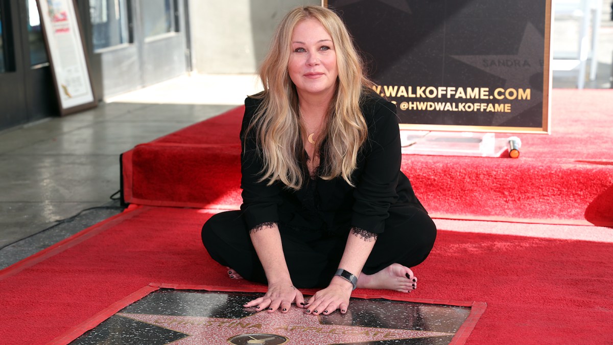 Christina Applegate sitting on the ground with her hands on her star on the Hollywood Walk of Fame