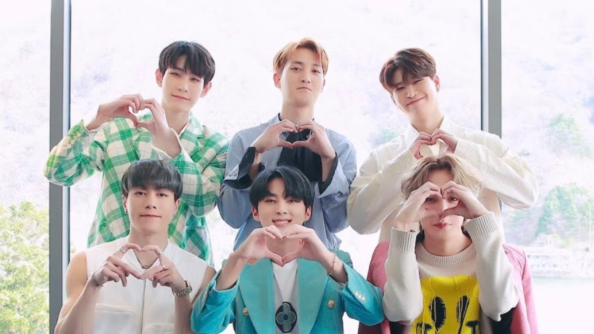 A group of K-pop singers making heart signs and smiling.