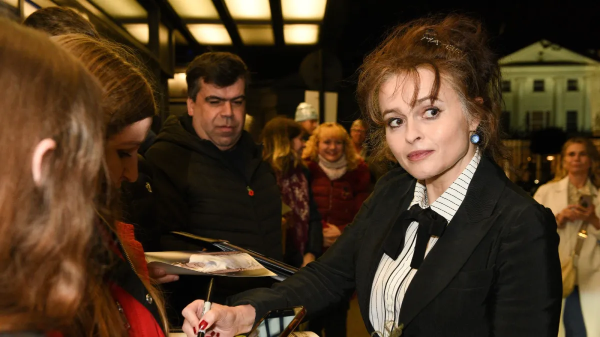 Helena Bonham Carter signs fan autographs at a red carpet event.