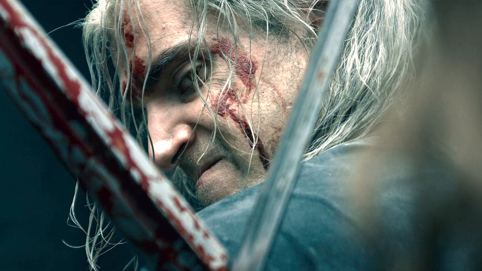 Perfil de Geralt de Rivia (Henry Cavill) brilhando através da abertura X de duas espadas conectadas