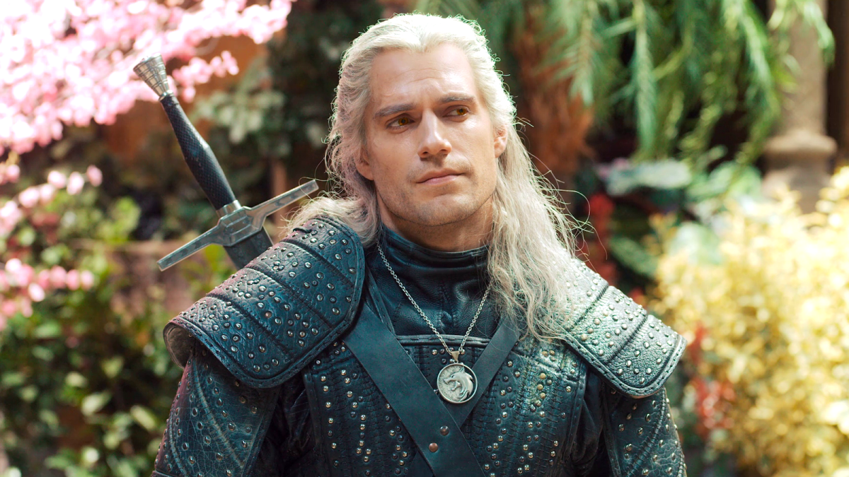 Geralt of Rivia (Henry Cavill) in his black armor surrounded by a garden of colorful flowers