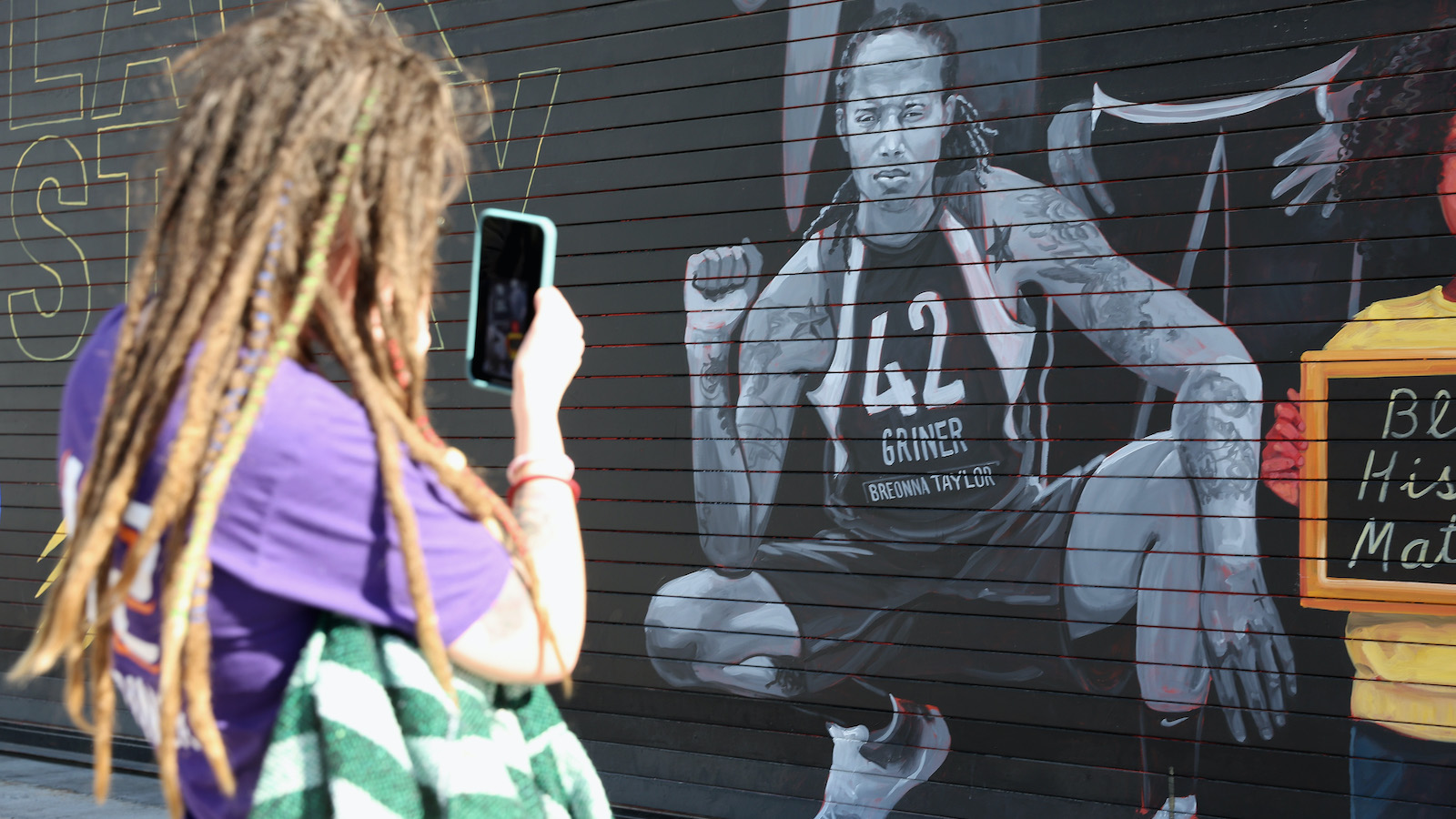 Phoenix Mercury fan Carley Givens takes a photo of a "Black Lives Matter" mural depicting Brittney Griner outside the Footprint Center 