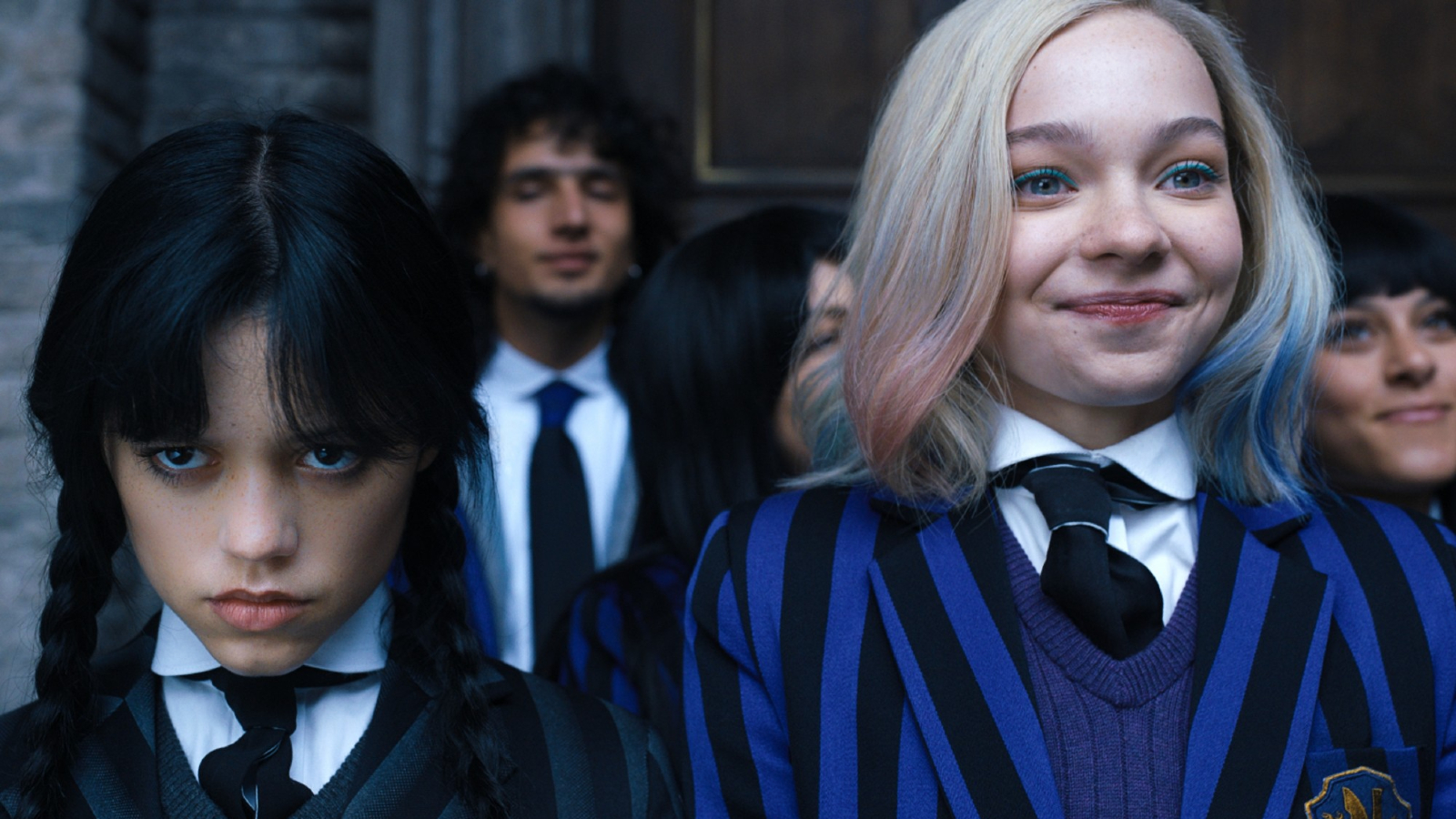 Enid Sinclair from Wednesday is smiling next to Wednesday Addams.