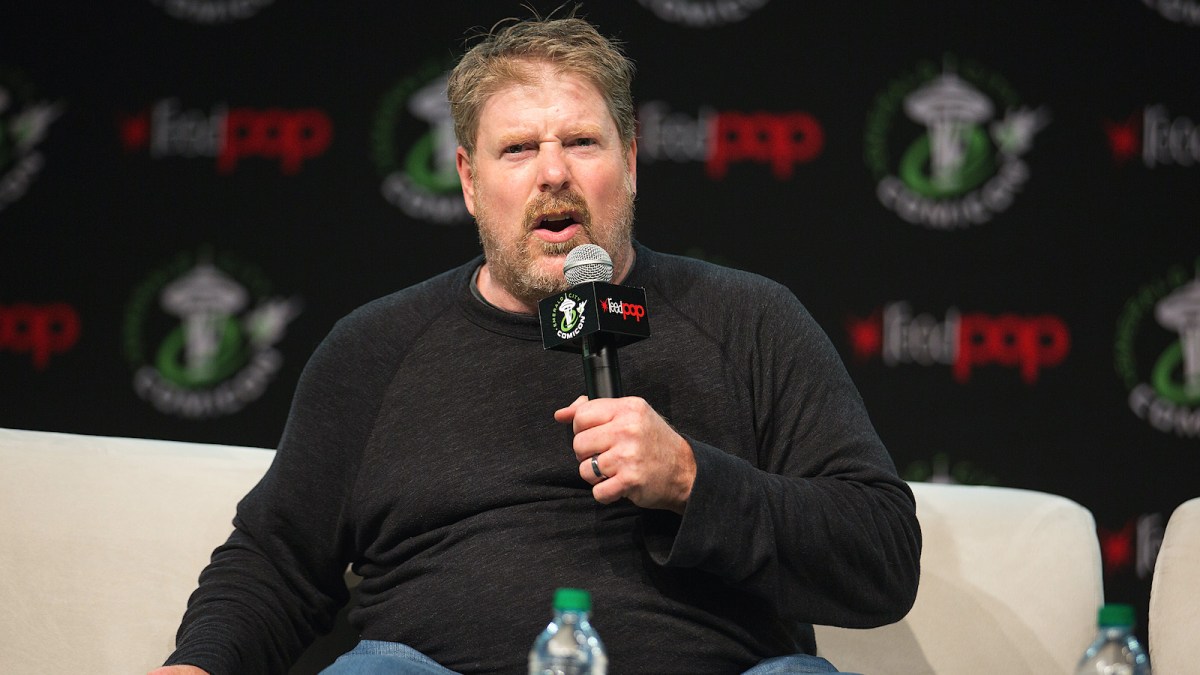 John DiMaggio on stage holding a microphone looking angry