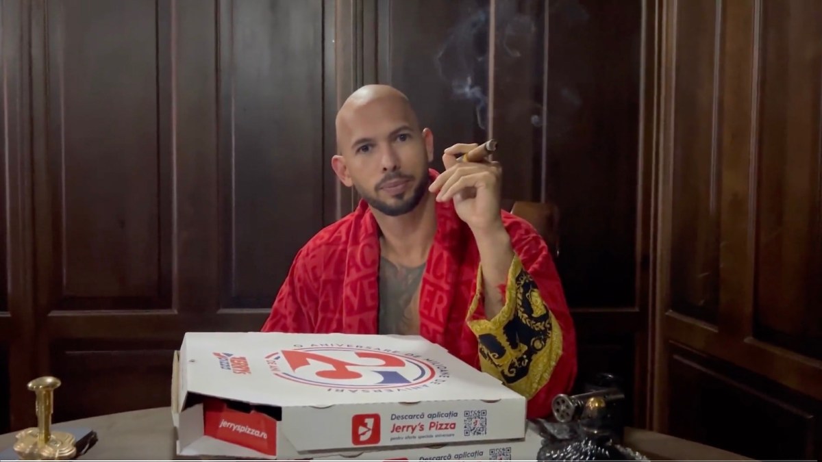 Andrew Tate smoks a cigar and poses with pizza box.