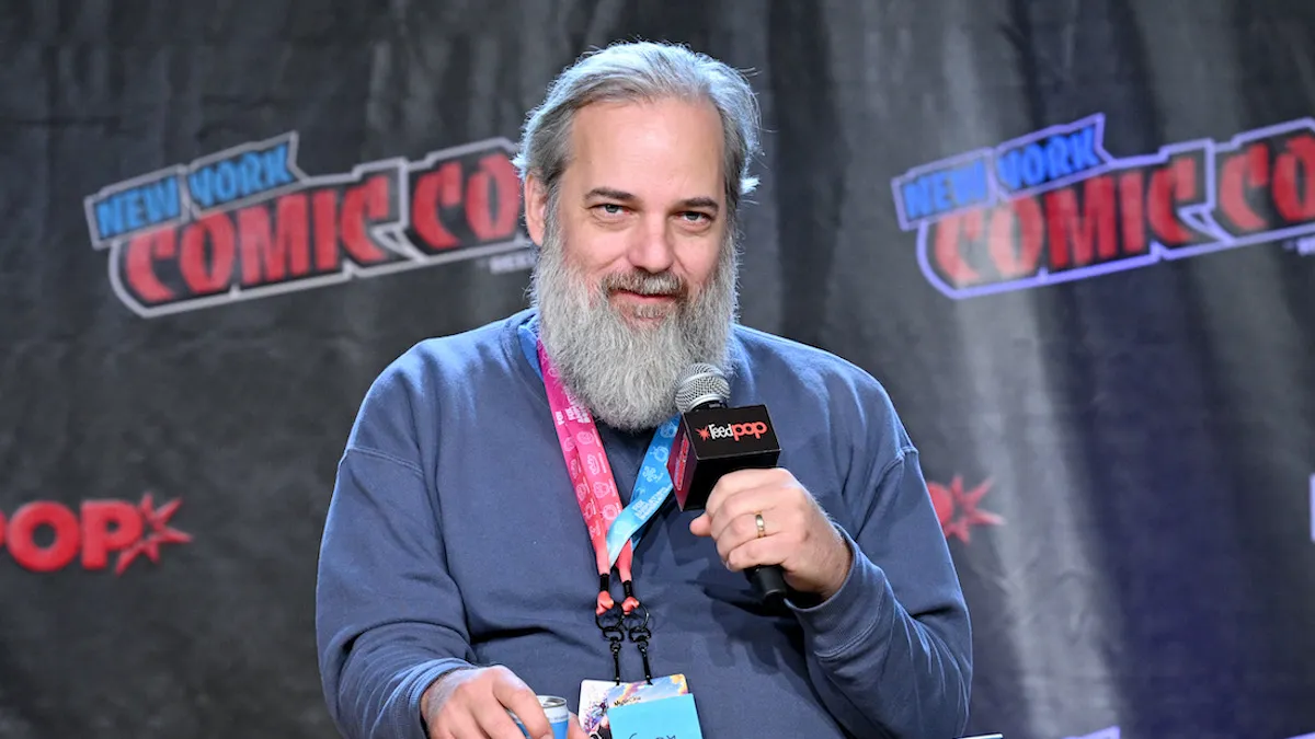 Dan Harmon on stage sitting in a chair with a microphone in his hand