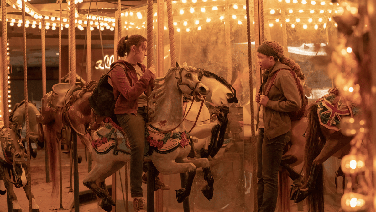 Riley (Storm Reid) and Ellie (Bella Ramsey) chatting on a horse carousel
