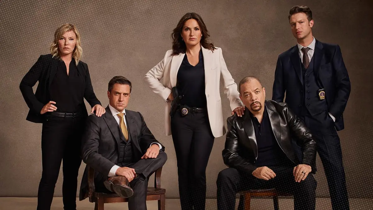 The cast of Law & Order poses for a picture in front of a brown background.