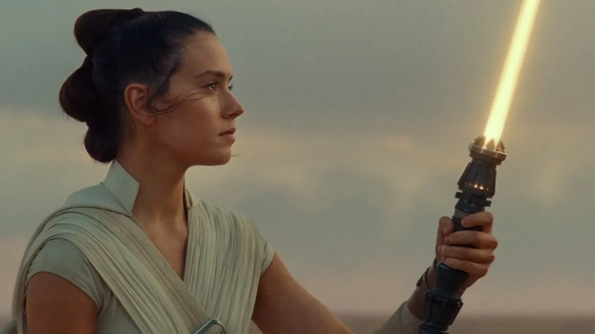 Rey looks at her orange lightsaber