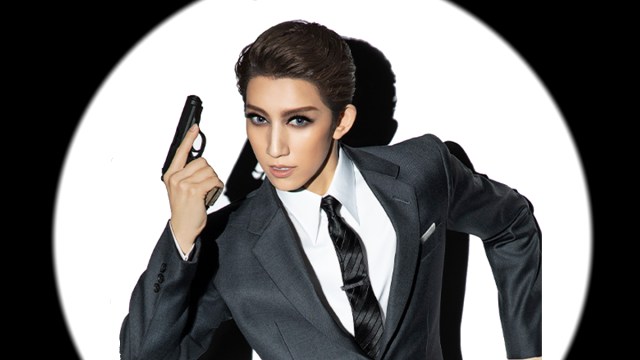 A lady dressed as James Bond holding his signature pistol.
