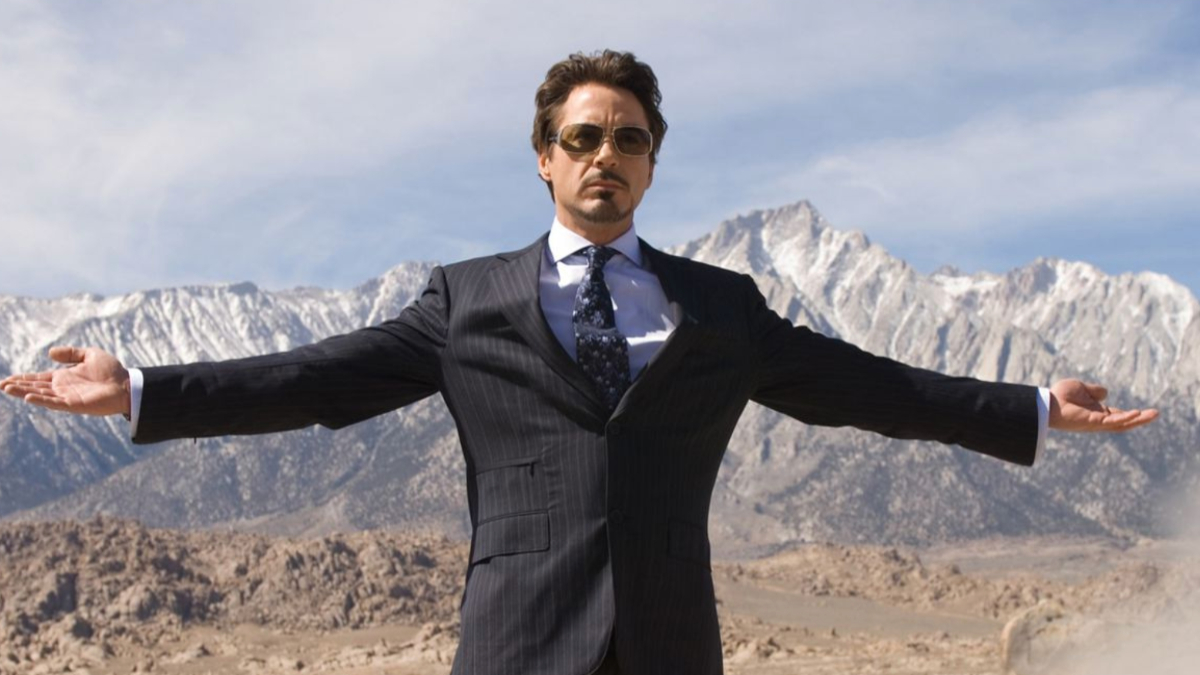 Robert Downey Jr.'s Tony Stark stands with his arms spread against a middle eastern desert in a screenshot of a famous moment from 2008's Iron Man.