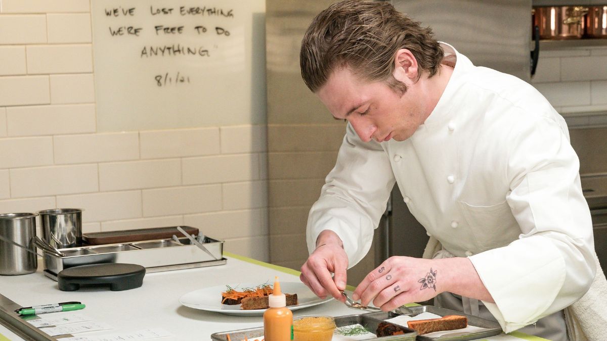 Jeremy Allen White from The Bear is plating a meal in the kitchen.