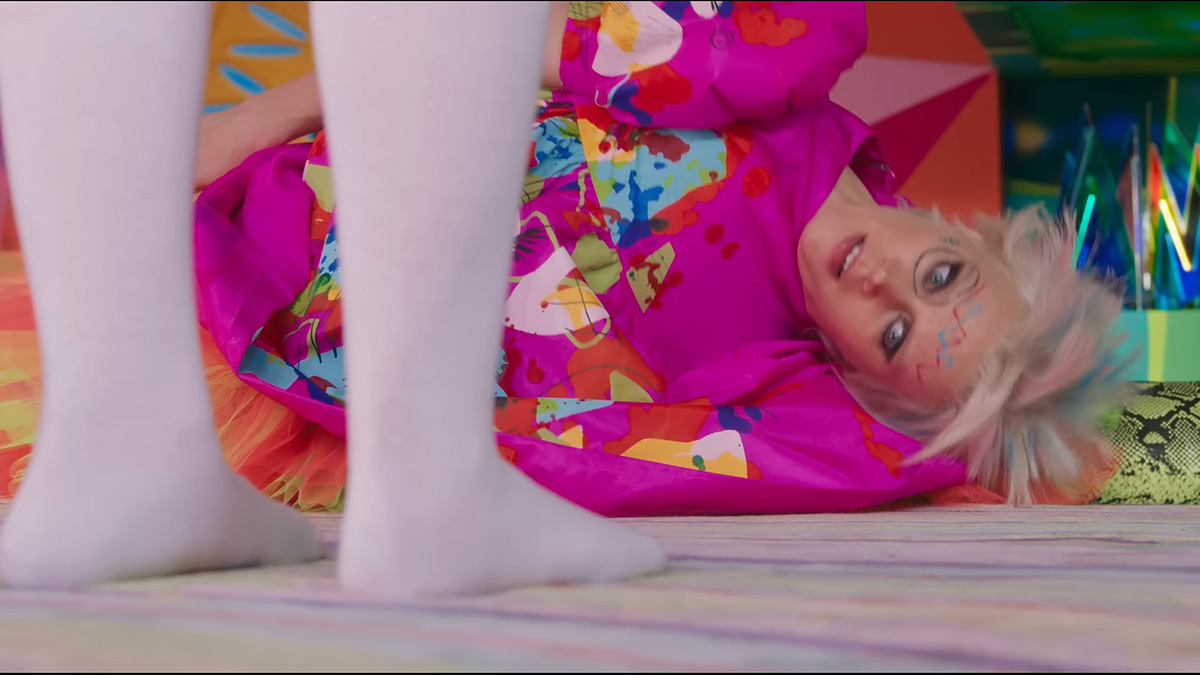 Kate McKinnon as Weird Barbie is lying down on the ground.