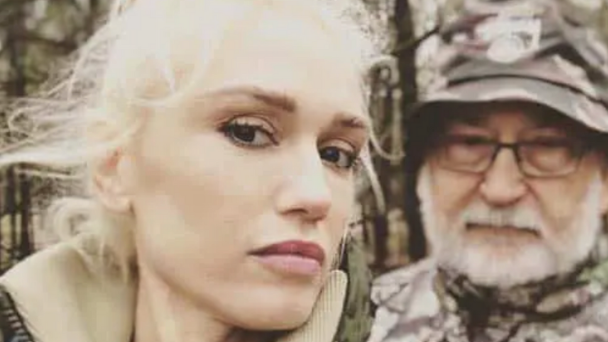 Gwen Stefani has her face angled and is taking a picture on a hike.