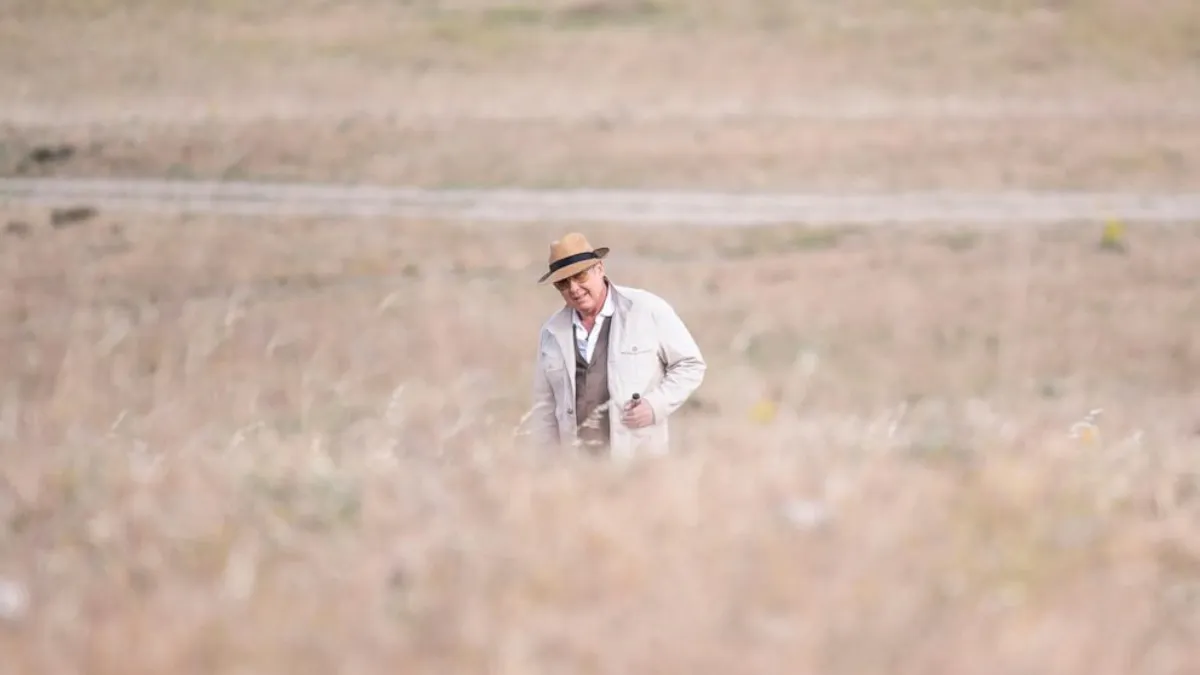 Red is standing in a field in "The Blacklist".