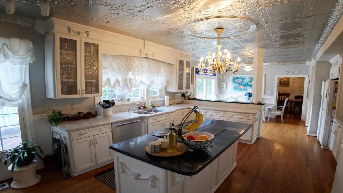 Uma cozinha ornamentada com teto de estanho e lustre brilhante e tratamentos de janela com babados.