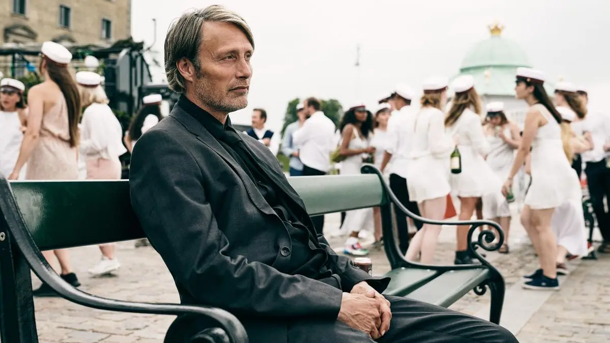 mads mikkelsen sitting on a bench in another round