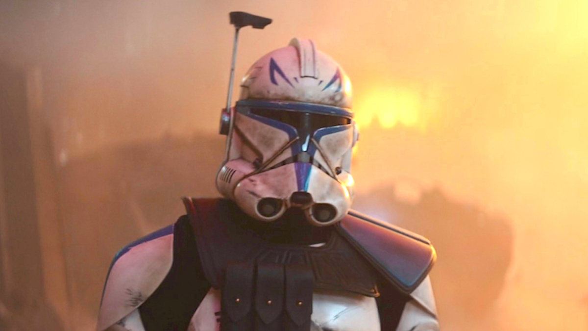 Captain Rex standing in a battlefield in his blue suit from Ahsoka